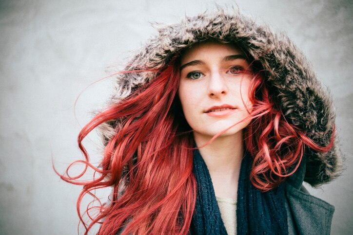 portrait of a young woman with pink colored hair and hoodie at a stormy day