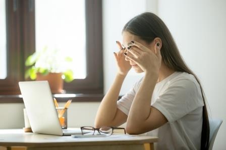 Tired ill female office worker massaging eyes, relieving stress from long hours working and looking at laptop screen. Woman suffering from headache. Concept of overwork, blurry vision (Tired ill female office worker massaging eyes, relieving stress fr