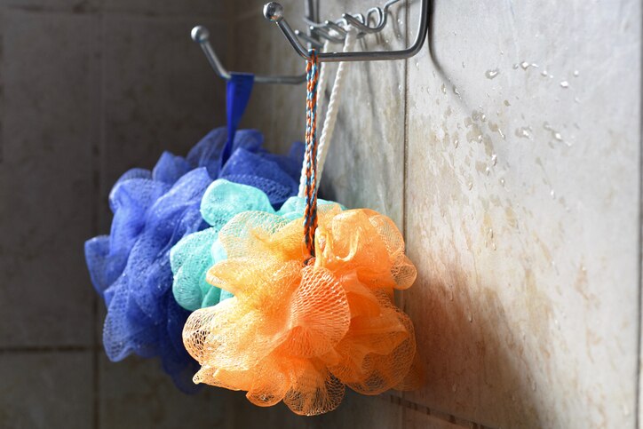 Light catches loofahs hanging from a rack.