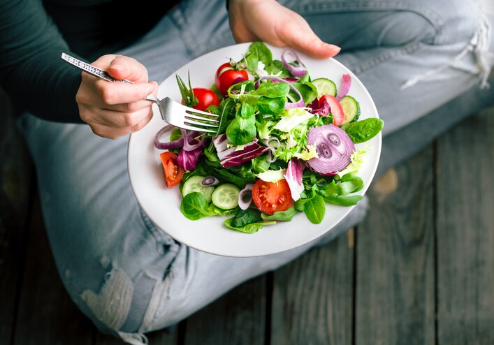 Fresh salad in the hands of the girl from above, the concept of healthy food and veggie