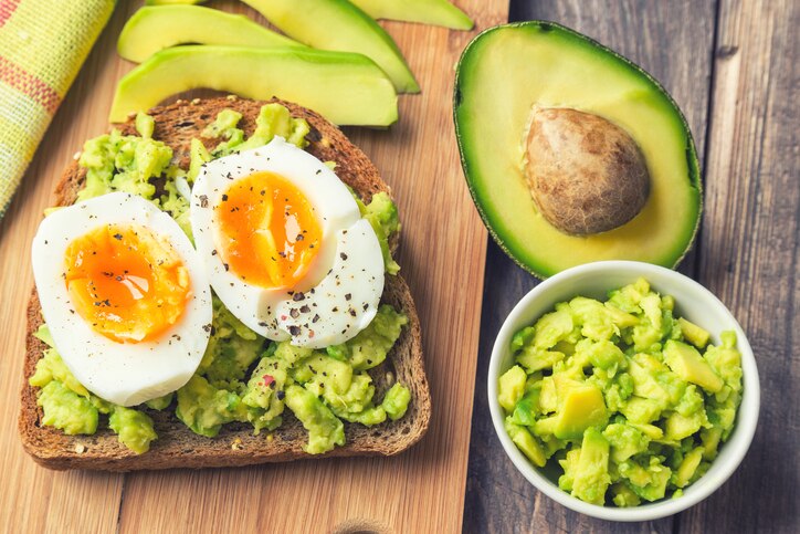 Toast with avocado and egg on rustic wooden background