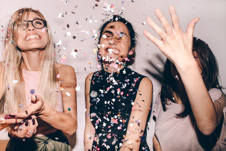 Photo of a group of young women celebrating their youth, femininity  and friendship - tossing a confetti in the air while dancing