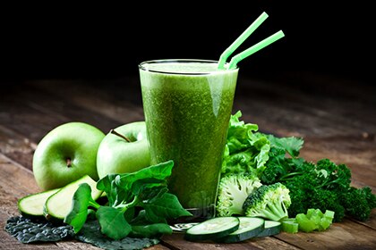 Glass of fresh green vegetable juice with two drinking straws on rustic wood table. The glass is surrounded by green vegetables like spinach, lettuce, broccoli, celery, green apples, parsley and cucumber. This is a drink used for detox diet. Predominant colors are green and brown.  DSRL studio photo taken with Canon EOS 5D Mk II and Canon EF 70-200mm f/2.8L IS II USM Telephoto Zoom Lens