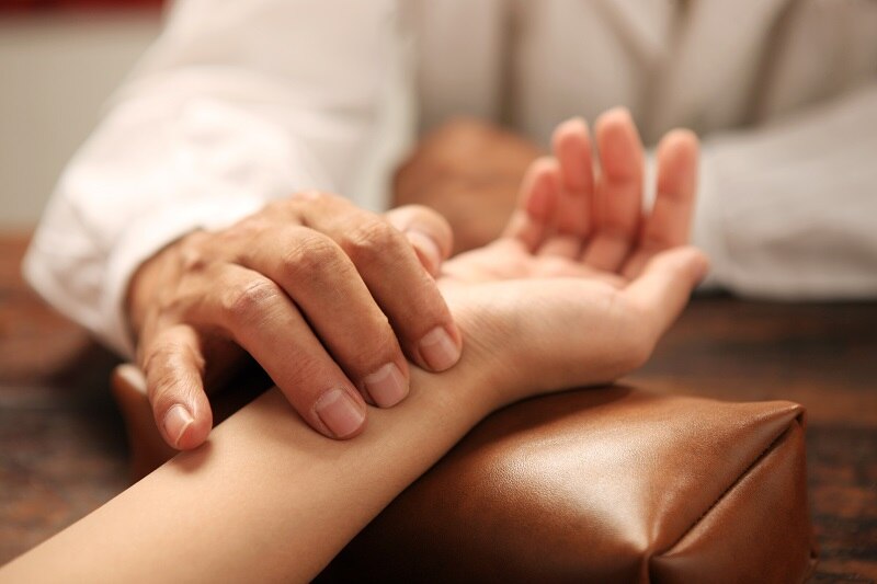 Chinese traditional herbalist doctor taking patient's pulse