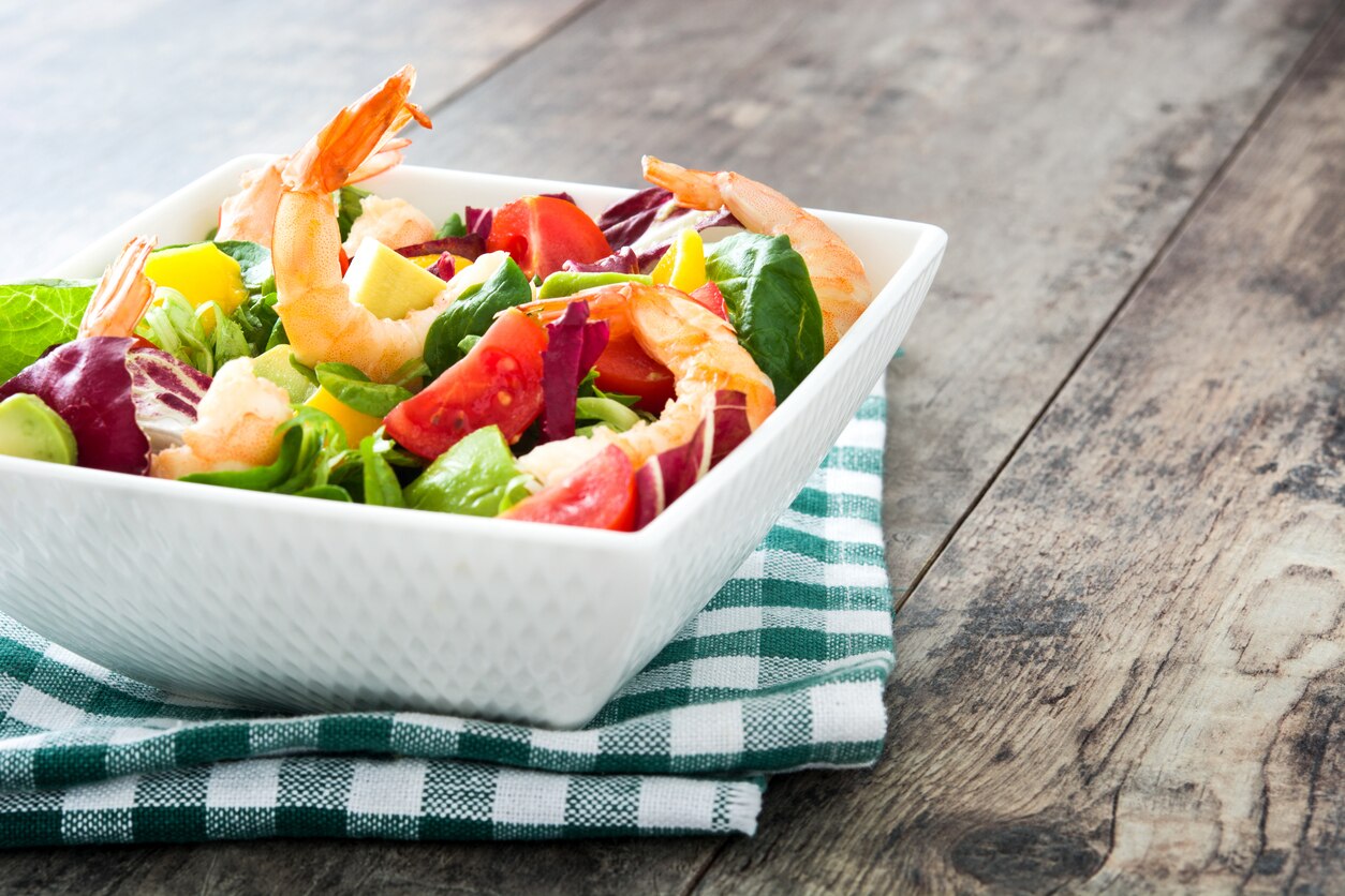 Shrimps salad with mango and avocado on wooden table