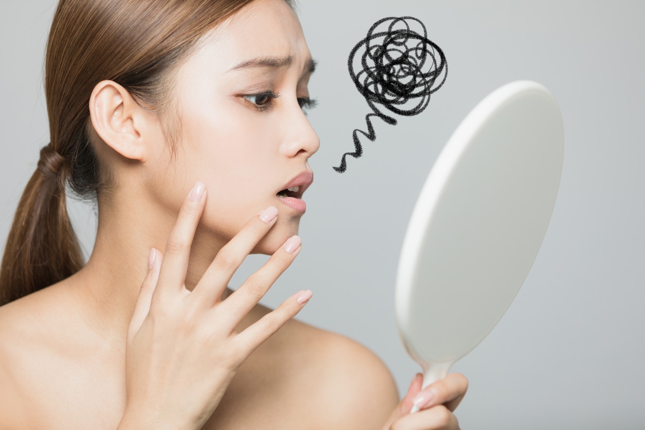 Young woman checking her skin. Skin care concept.