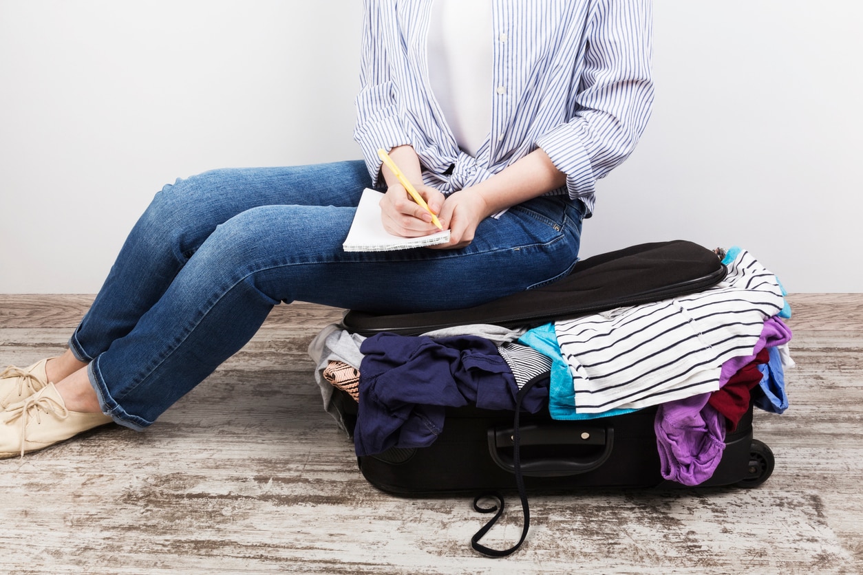 Young girl casually packs black suitcase